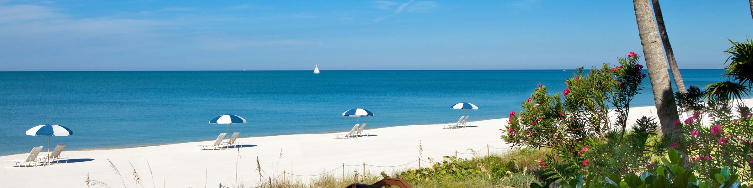 Beach view with lounge chairs and umbrellas in Naples, FL